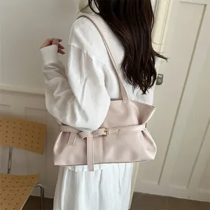 Detail of light pink shoulder bag featuring decorative belt buckle and glossy leather texture