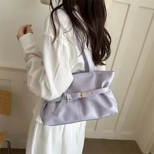 Detail view of lavender faux leather shoulder bag with buckle strap on a model