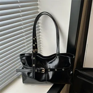 Detail of glossy black faux leather tote with metallic belt buckle and eyelet hardware