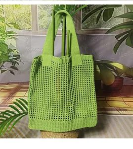 Dettaglio della borsa tote in maglia verde con design a tracolla larga e piatta