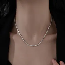 Dettaglio della collana con croce in zirconi colorati su una modella in blazer scuro