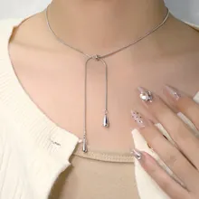 Dettaglio della collana a Y in argento con ciondoli a goccia lucidi indossata sul collo