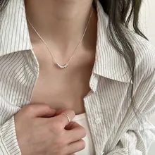 Dettaglio della collana con sfere d'argento e anello minimalista con camicia a righe