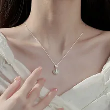 Primo piano del ciondolo a cuore in giada su catena d'argento indossato da una modella