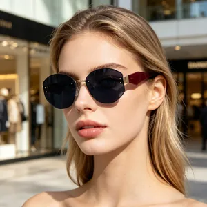 Close-up of rimless polygon sunglasses with wine red temples and gold bridge detail