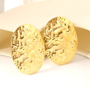 Close-up of vintage large oval golden earrings with irregular hammered texture detail
