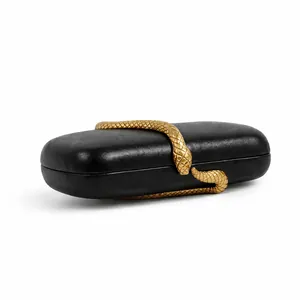 Macro view of black leather evening bag featuring a detailed golden snake ornament