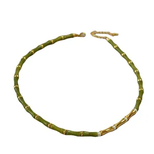 Bamboo style green jade bead necklace with golden accents and white pearls on white background