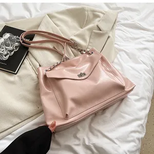 Detailed view of pink patent leather tote bag with silver clasp and chain strap accents