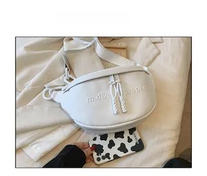 Close-up of white PU leather crescent bag with embossed letters next to a phone for size comparison
