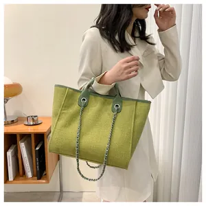 Détail de la texture du cabas tissé vert avocat avec chaîne argentée et poignée en cuir