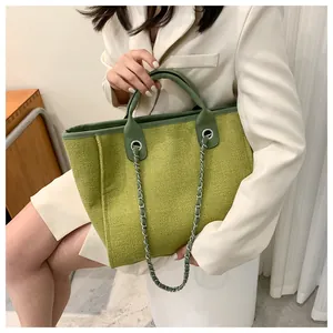 Détail du cabas en tweed vert avec bordure en cuir et bandoulière chaîne argentée