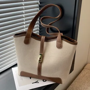 Chic canvas tote bag with brown leather trim and golden lock detail in natural light