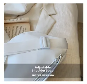 Detail of adjustable shoulder strap and white buckle on textured PU leather bag