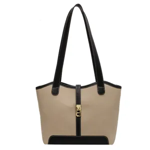 Fashion canvas bucket bag in beige fabric with black leather handles and golden lock