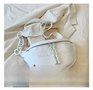 Detail of white PU leather saddle bag with embossed letters and large plastic chain