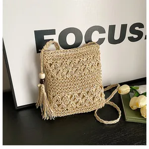 Detail showing hollow flower weave pattern and long tassels on handmade straw bag
