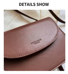Detail of brown PU leather crossbody bag showing fine stitching and embossed logo