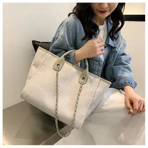 Détail du sac seau en toile beige avec garniture en cuir gris et chaîne argentée
