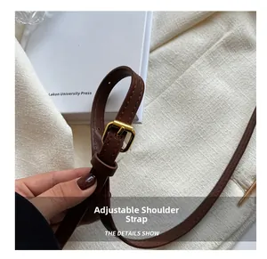 Detail of adjustable brown leather shoulder strap with a golden metal pin buckle
