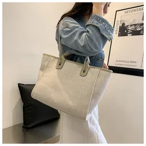 Détail d'un grand sac cabas tissé avec garniture en cuir vert gris et poignées à chaîne