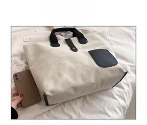 Size comparison of a beige canvas tote bag with black pockets against a smartphone