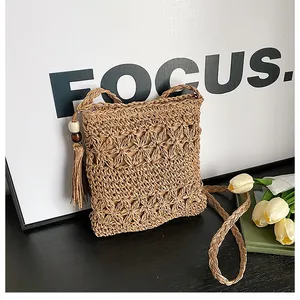 Close-up of handmade hollow straw crossbody bag with tassel and wooden bead details