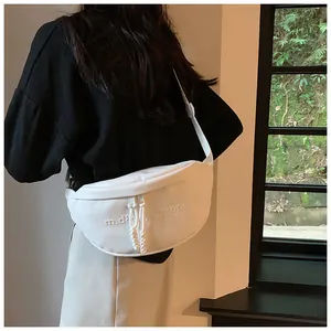 Detail of white half-moon crossbody bag with embossed letters and woven zipper pulls
