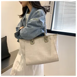 Détail du sac cabas en lin avec bordures en cuir et bandoulière en chaîne argentée