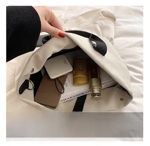 Macro view showing spacious interior capacity and snap button of white canvas tote bag