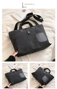 Detail view of large black canvas tote bag with leather buckle and metal button closure