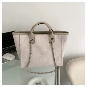 Gros plan du sac cabas beige tissé avec chaîne métallique et lanières en similicuir