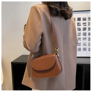 Detailed view of the brown leather flap crossbody bag with golden buckle on a model