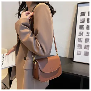 Detail of adjustable leather strap and gold-tone metal hardware on a brown saddle bag