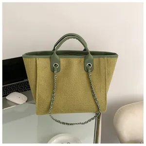Détail du sac cabas tissé vert avec bandoulière chaîne sur un bureau blanc
