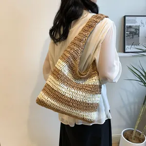 Detail of striped woven straw tote bag featuring brown and cream wide bands and wide strap