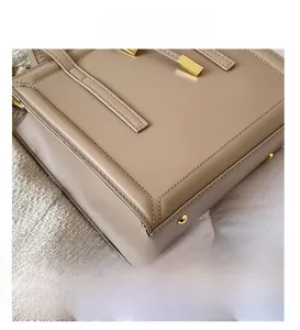 Detailed view of beige leather bag base with golden protective studs and double stitching