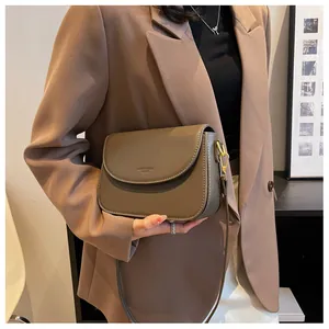 Close-up of a brown matte leather crossbody bag with contrast stitching and gold buckle