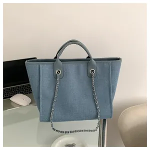 Détail du sac cabas bleu tissé avec bandoulière chaîne argentée et poignées circulaires