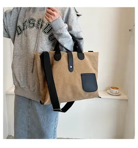 Detail of khaki canvas tote bag featuring black leather straps and detachable shoulder strap