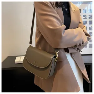 Detail of tan leather crossbody bag featuring gold buckle and neat stitching on shoulder strap