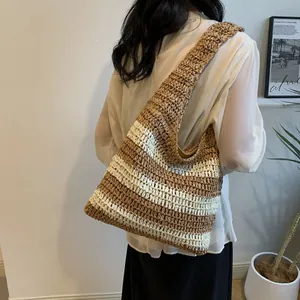 Detail of the woven texture on a large striped straw tote bag with wide shoulder straps