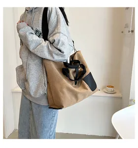 Brown canvas tote bag with black straps worn by model for daily commute and university