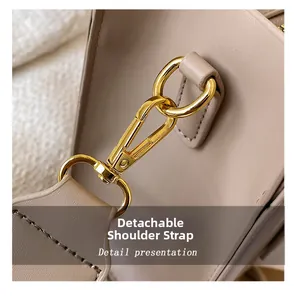 Detail of the detachable shoulder strap with light gold metal hardware on beige handbag