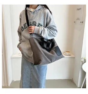 Detail of grey canvas tote bag with black leather patch and adjustable shoulder strap