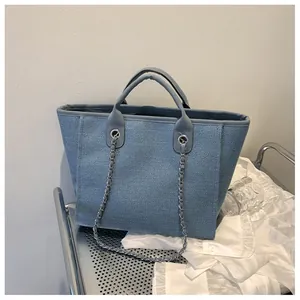 Détail du sac cabas en tweed bleu montrant la texture tissée avec chaîne argentée et poignée