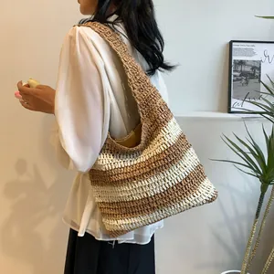 Detail of hand-woven straw tote bag with striped pattern and wide shoulder strap