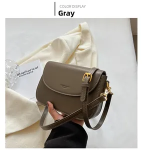 Detail of dark gray crossbody bag with textured faux leather and golden hardware buckle