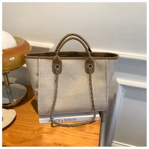 Détail du sac seau en toile avec bordure en cuir et chaîne argentée sur table en bois