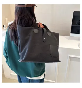 Detail of a black canvas tote bag showing high-quality leather stitching and magnetic closure